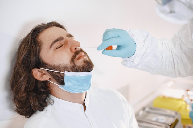 Doctor protective suit and surgical face mask. Cotton swab from the throat and nose of the patient's. Coronavirus test, test for covid-19 infection in a pandemic.