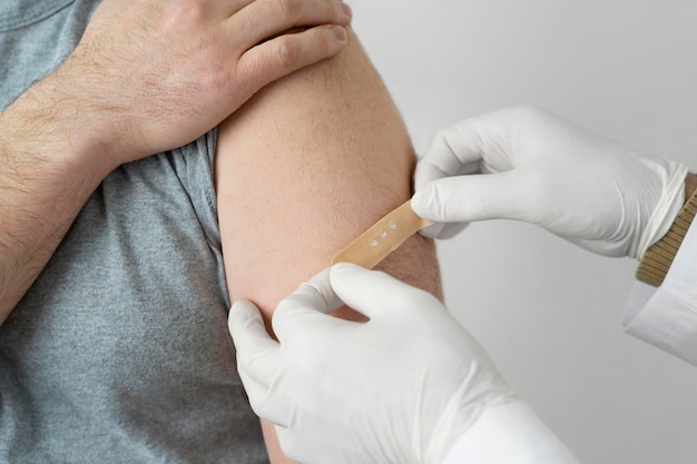 ワクチン注射後に男性患者の腕に包帯を巻く医師