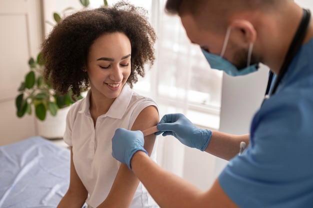 Foto gratuita medico che mette un cerotto su un braccio del paziente dopo la vaccinazione