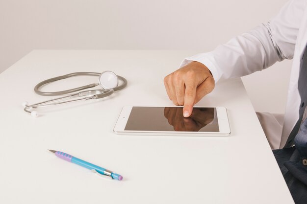 Doctor's hand touching tablet's screen