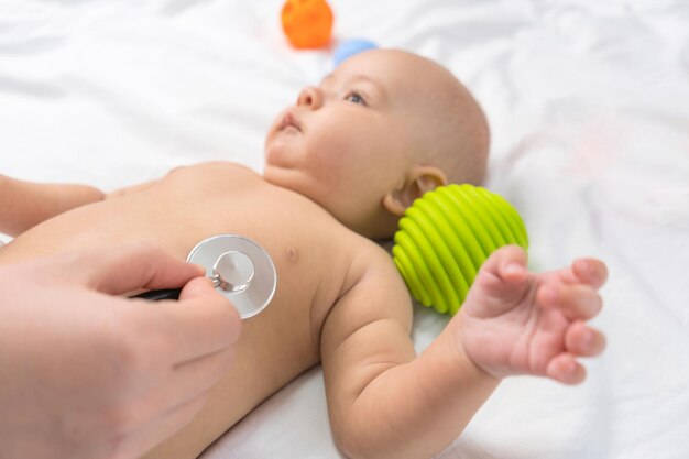Doctor's hands hold a stethoscope and listen to the heart of a newborn. selective focus