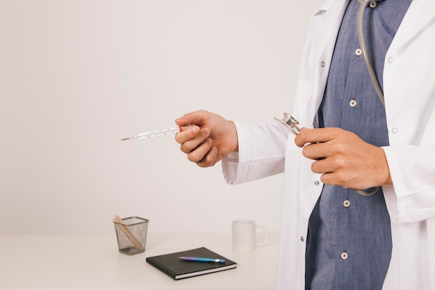 Free photo doctor's hands with a thermometer and stethoscope