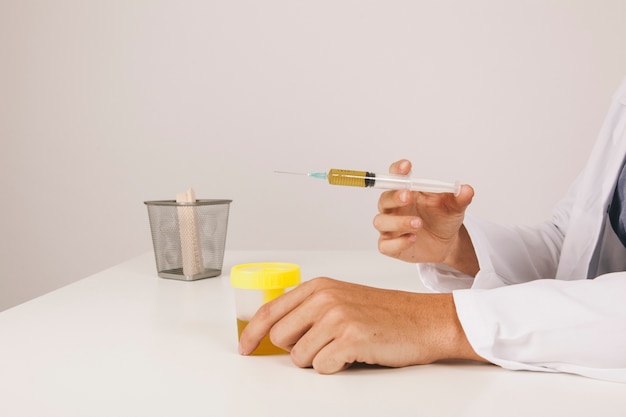 Doctor's hands with urine test and syringe