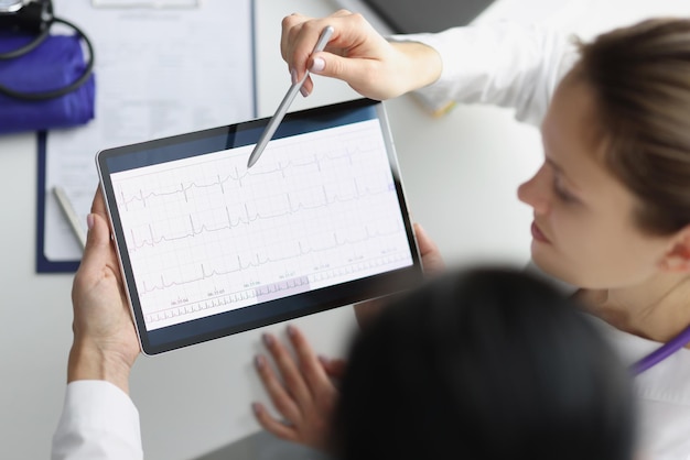 Doctor show digital tablet screen with heart cardiogram result to coworker