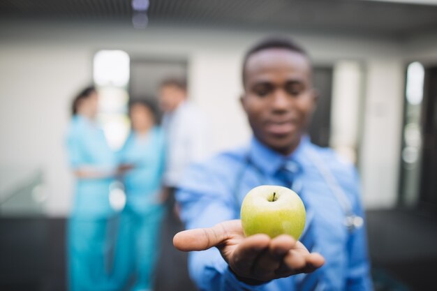 Doctor showing green apple in hospital corridor