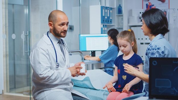 건강 문제가 있는 아이를 위한 어머니 약을 보여주는 의사. 캐비닛 병원에서 의료 서비스 방사선 치료 검사를 제공하는 의료 전문가 의사