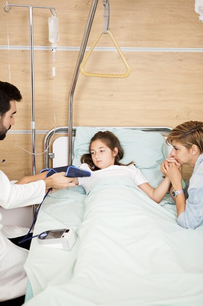 Doctor taking arterial tension of her patient in hospital room