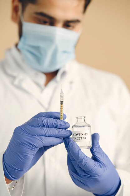 Doctor taking vaccine with syringe from ampoule, epidemic prevention.