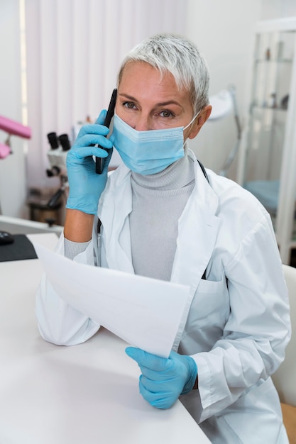 Free photo doctor talking at her phone while wearing a face mask