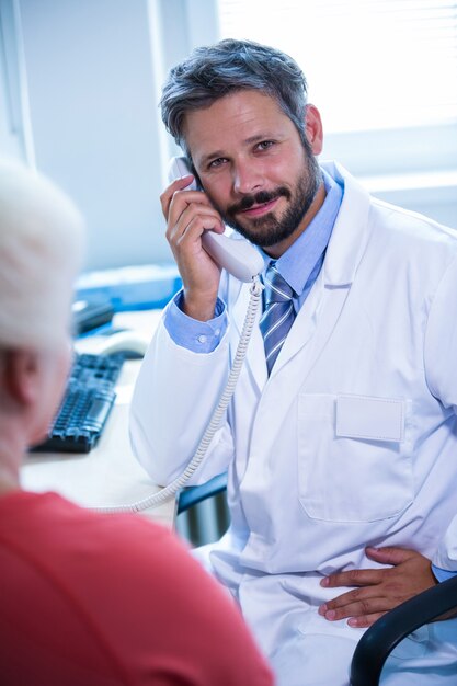 Doctor talking on landline phone in medical office at hospital