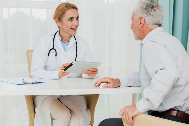 Free photo doctor talking to patient while holding tablet