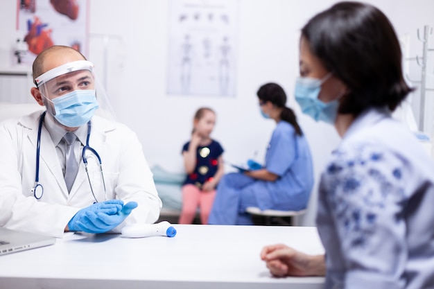 Free photo doctor talking with parent while nurse consulting child wearing protection mask. health pediatrician specialist providing health care services consultations treatment in protective equipment.