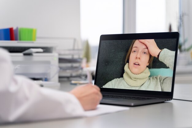 Doctor teleconsulting patient on laptop