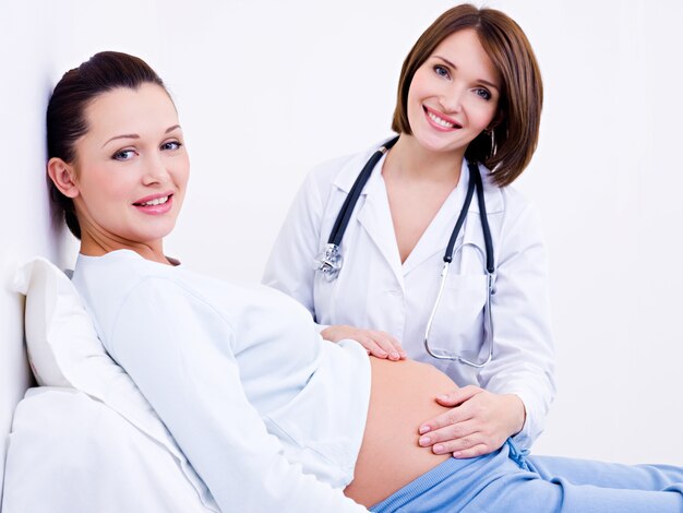 Доктор трогает живот беременной женщины