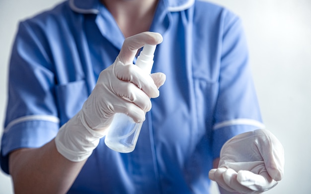 医師は、コロナcovid-19ウイルスに対する白い手袋をした消毒剤を使用しています。