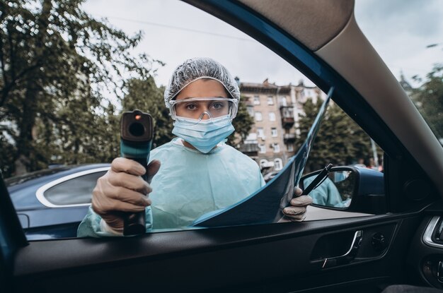 Doctor uses infrared thermometer gun to check body temperature