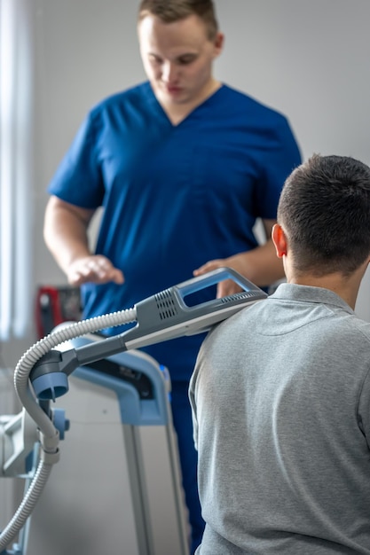 Foto gratuita medico che utilizza la macchina per trattare le spalle dei pazienti