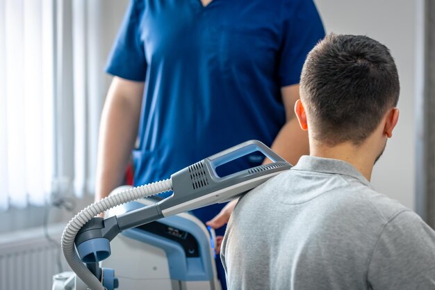 Foto gratuita medico che utilizza la macchina per trattare le spalle dei pazienti