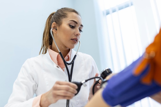 Doctor using sphygmomanometer with stethoscope checking blood pressure to a patient in the hospital