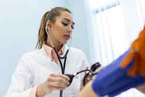 Free photo doctor using sphygmomanometer with stethoscope checking blood pressure to a patient in the hospital