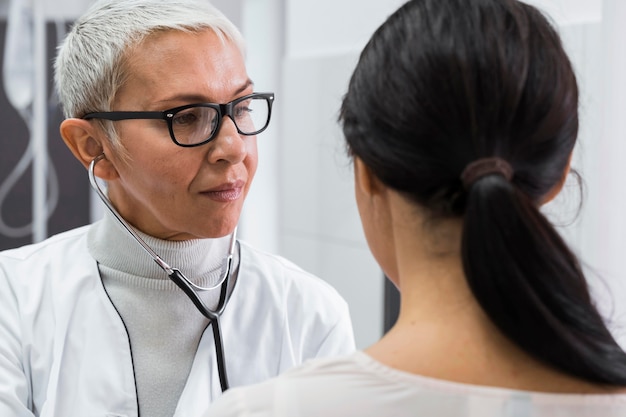 Doctor using a stethoscope on a female patient