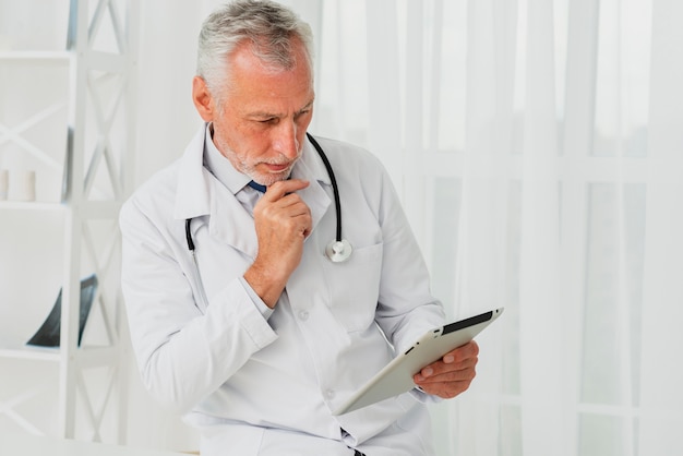 Doctor using tablet while hand is on chin