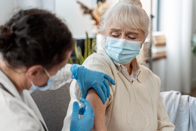 Foto gratuita medico che vaccina una donna anziana