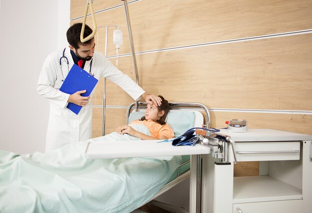 病室で患者の女の子を訪問する医師