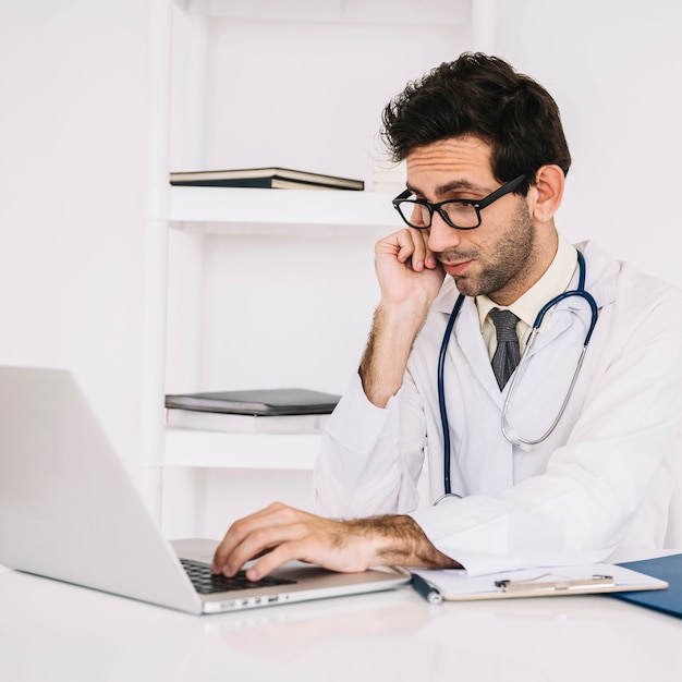 Doctor wearing eyeglasses using laptop