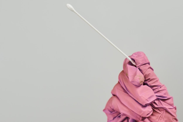 Врач в розовых перчатках держит тест на коронавирус