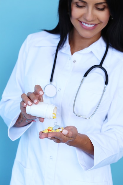 Doctor wearing white robe and stethoscope holding pills