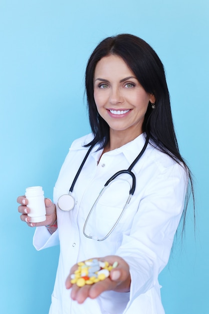 Doctor wearing white robe and stethoscope holding pills