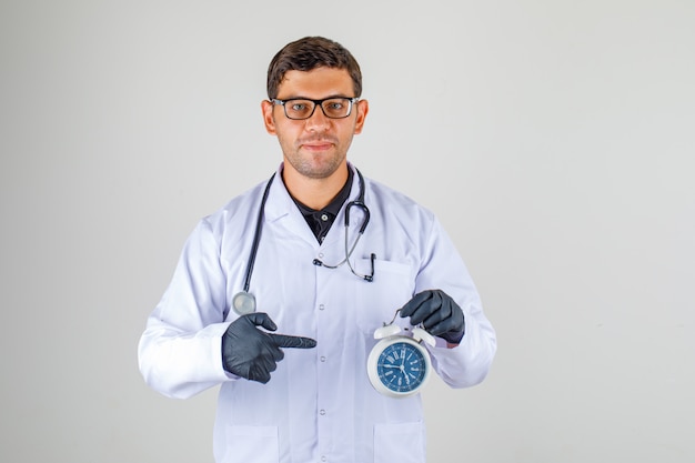 Доктор в белом халате со стетоскопом и будильником