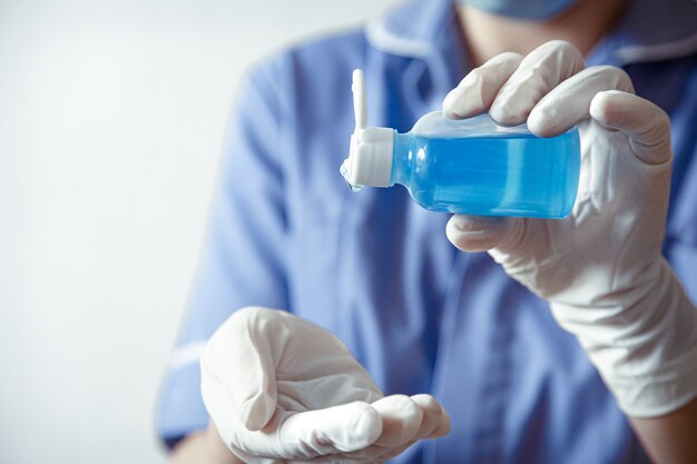 흰 장갑을 끼고있는 의사는 코로나 코 비드 -19 바이러스의 확산을 막기 위해 손 소독제를 사용합니다.