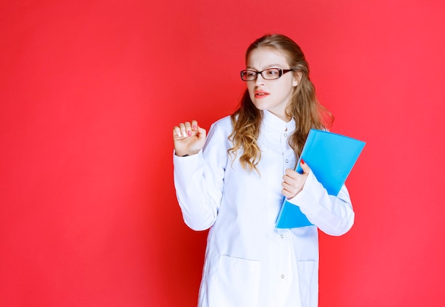 Doctor with a blue folder looks tired .