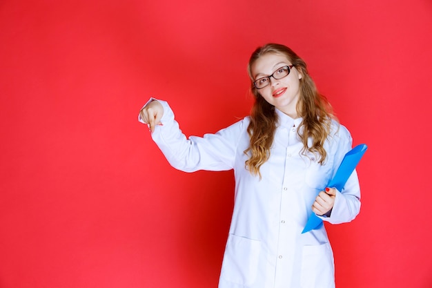 Doctor with a blue folder pointing to the downside.