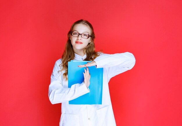 Doctor with eyeglasses holding a blur folder.