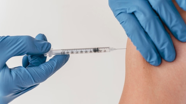 Free photo doctor with gloves administering vaccine to patient