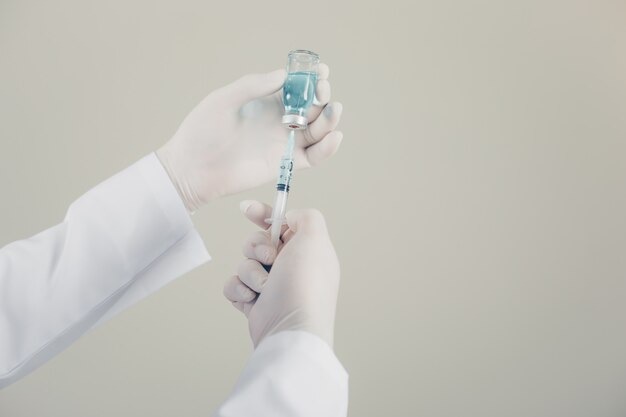 Doctor with gloves drawing medicine out of a vial side view