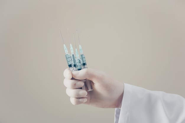 Doctor with gloves holding syringes in his hand, side view.