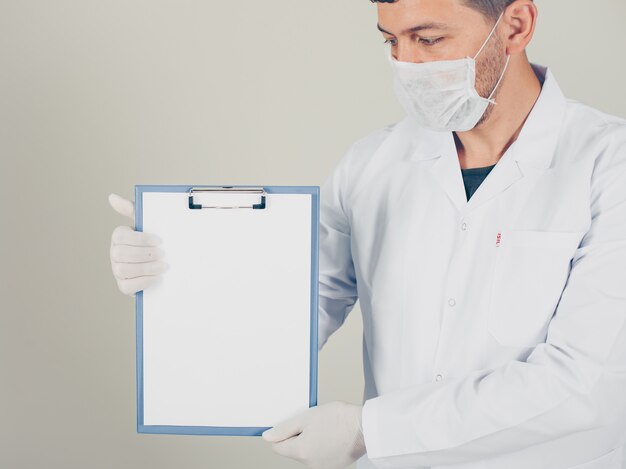 Doctor with gloves looking and holding paper holder vertically. side view.