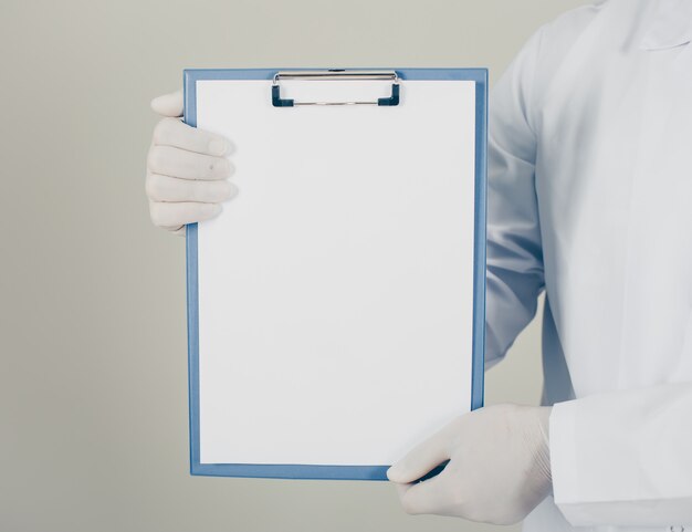 Doctor with gloves looking and holding paper holder vertically. side view.