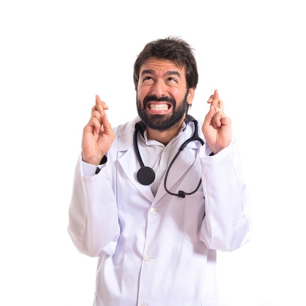 Doctor with his fingers crossing over white background