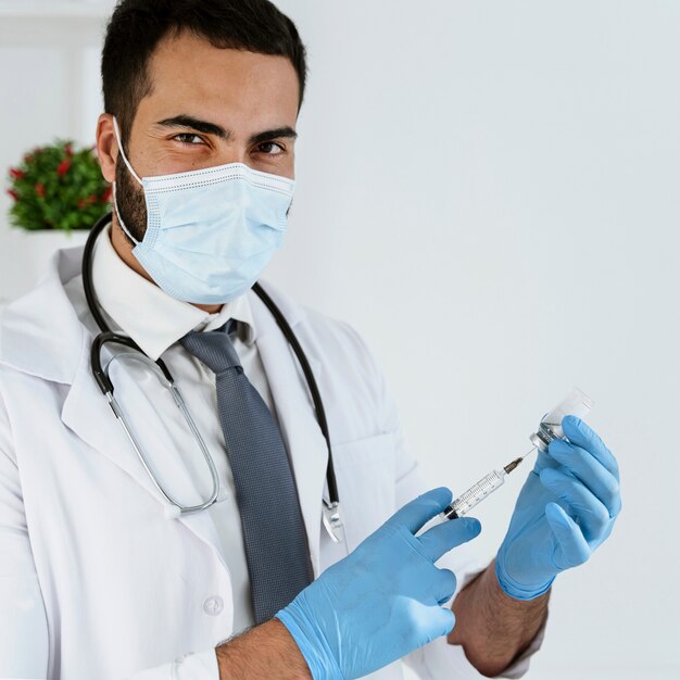 Doctor with medical mask holding a syringe