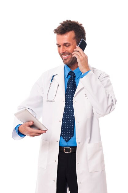 Doctor with mobile phone checking something on digital tablet