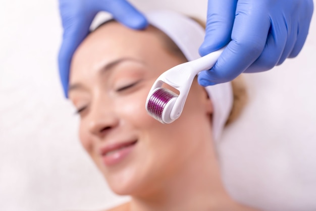 Doctor with rubber gloves doing a plastic face surgery on a happy young female