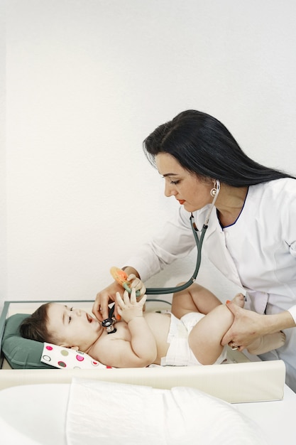 Free photo doctor with stethoscope. baby without clothes. examination by a doctor.