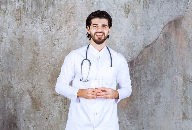 Doctor with a stethoscope holding a glass of pure water