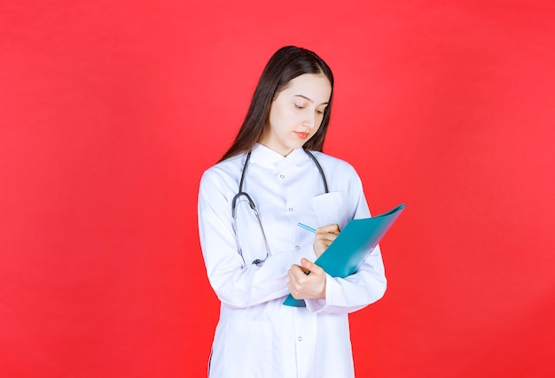 Doctor with a stethoscope holding the history of the patient and making remarks or corrections.