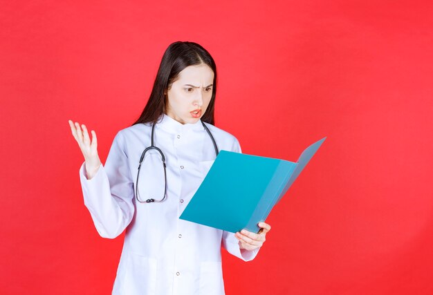 Doctor with a stethoscope holding the history of the patient, reading it and getting nervous.